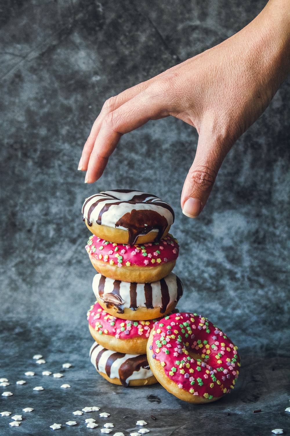 A stack of doughnuts with a hand reaching for them