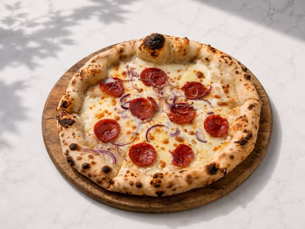 Pepperoni pizza with red onion on a wooden board in dappled daylight — shot on site by a Splento creator