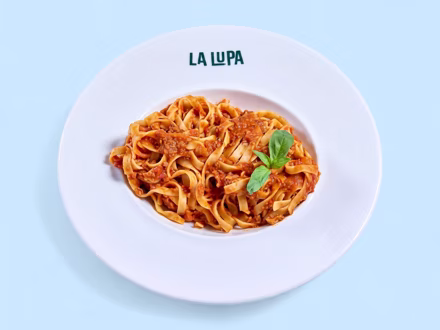 Tagliatelle in tomato sauce topped with basil, shot from above — menu photography for listings